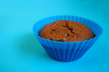 gluten-free chocolate muffin with apples in a blue silicone mold stands on a blue background, side view, cooked at home