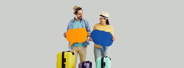 Two people with orange and blue speech balloon dialogue cards standing isolated on gray studio...