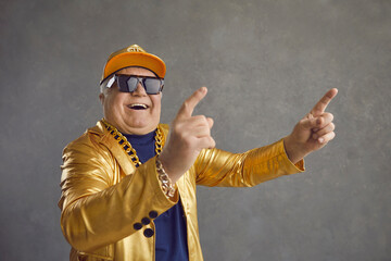 Funny happy rich senior man in golden party jacket, baseball cap and bling gold chain necklace...