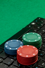 Gambling chips on computer keyboard on green background