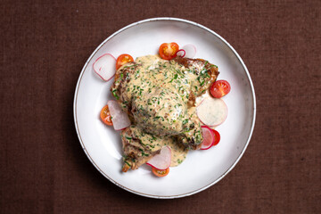 view from above chicken dish with cream sauce with radish and tomato.