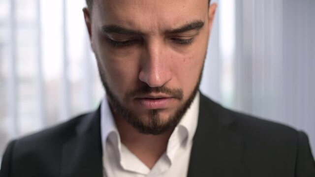 The camera zooms in on the face of a young manager, who is discontentedly examining work papers. Young male boss or an ordinary employee of the company examines documents