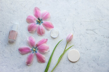 Obraz na płótnie Canvas nail polish firming, sponge, tulips and a jar of powder stand on a light background, cosmetic minimalism