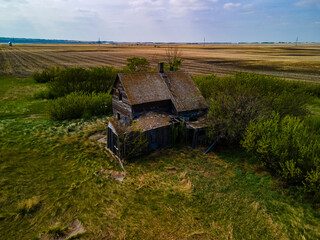 An aerial view of old abandoned farm houses that were left to be reclaimed by nature. These structures are in a state of disrepair and are starting to collapse as they were forgotten on the prairies.