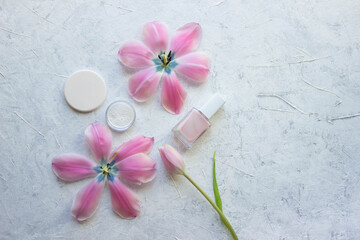 nail polish firming, sponge, tulips and a jar of powder stand on a light background, cosmetic minimalism