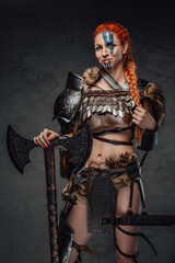 Obraz premium Serious nordic female warrior with axe and armour in dark background
