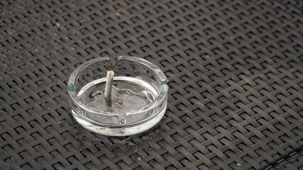 Ashtray with extinguished cigarette on the table. Bad habits concept. Ashtray for cigarettes, side...