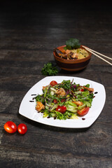 salad with shrimp and herbs and a plate with ramen on a wooden background