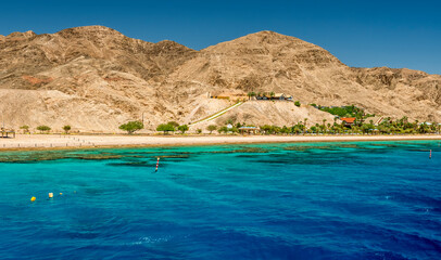 Beautiful coral reefs of the Red Sea, sandy beaches, tourist resort hotels and mountains near...