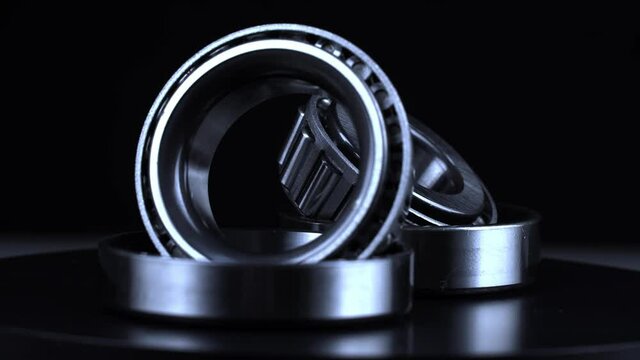 Cyclic seamless video with bearings rotating on a turntable on a black background. The two bearings rotate around their axis. Mechanism concept and equipment. Close-up, macro.