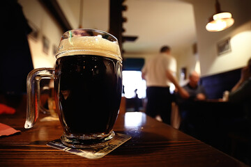 mug of dark beer in the interior of  pub / pint of beer with foam on a served table in  beer restaurant in Czech Republic