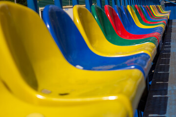 Empty stands, a grandstand with one row of plastic multi-colored seats, chairs for fans in a sports stadium.