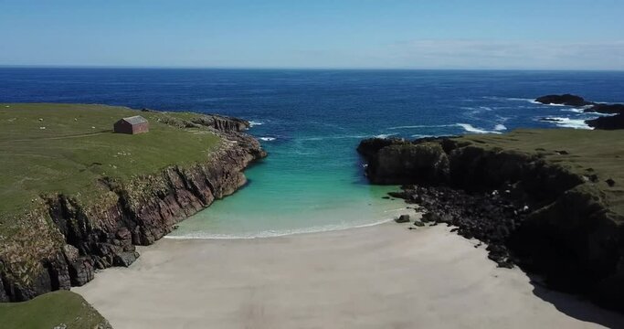 4k aerial clip of Port Stoth beach and cliffs at Butt of Lewis, Isle of Lewis, Outer Hebrides, Scotland. Sunny day with blue sky. Turquoise sea, white sand, grass on cliffs, no people.