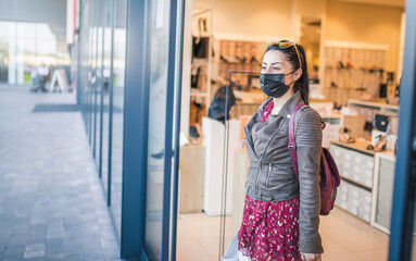 A woman comes out of a boutique with a mask on her face .covid-19