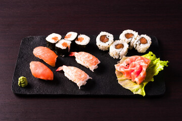 mixed sushi on black tray. dark wooden background