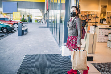 A woman comes out of a boutique with a mask on her face .covid-19