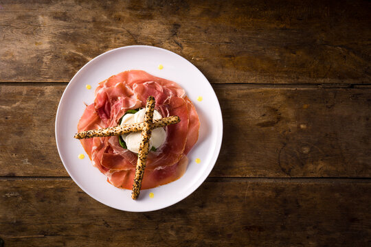 plate with San Daniele raw ham and buffalo mozzarella from Campania on wooden table. top view