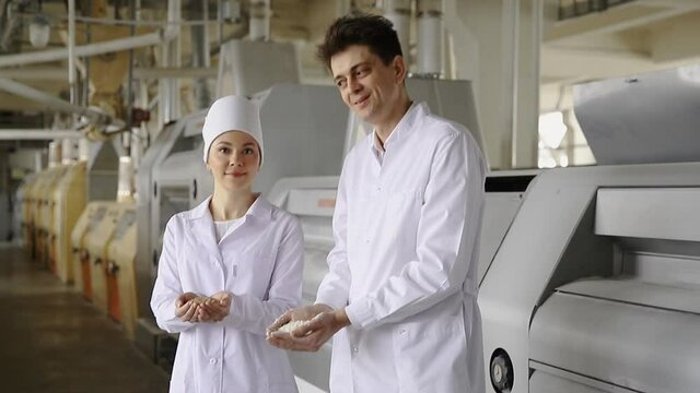 Two Worker holds grain for production of white flour in automated modern mill.