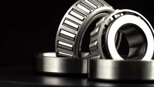 Cyclic seamless video with bearings rotating on a turntable on a black background. The two bearings rotate around their axis. Mechanism concept and equipment. Close-up, macro.
