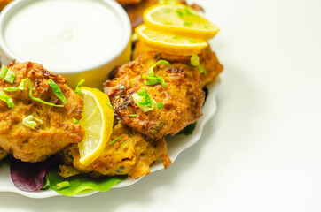 Delicious onion bhaji fritters served on ceramic plate with white dip
