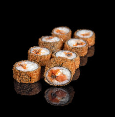 A close up of food fried sushi rolls isolated on black. reflection