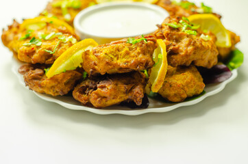 Delicious onion bhaji fritters served on ceramic plate with white dip