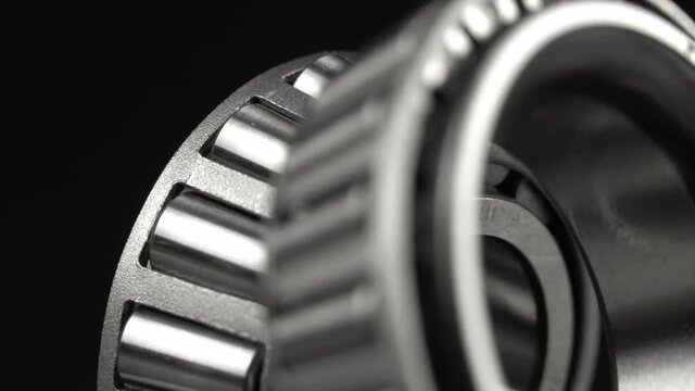 Cyclic seamless video with bearings rotating on a turntable on a black background. The two bearings rotate around their axis. Mechanism concept and equipment. Close-up, macro.