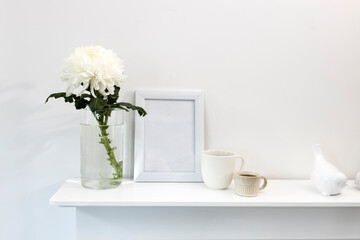 Large chrysanthemum in a glass vase. Photo frame with place for text, two corrugated cups with coffee and ceramic figurines of birds on the table. Office decoration.