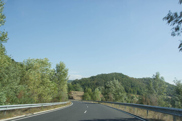 Empty asphalt road winding through green hills, trees and plants, nature, Greece, greek roads