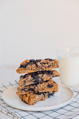 Stack of homemade oatmeal scones with berries stacked on white plate and glass of plant based milk. Vegan sweet baked food. Gluten free pastry. Healthy breakfast.