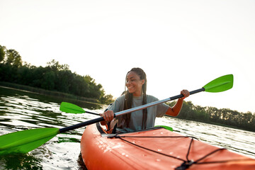 Joyful young woman smiling, enjoying a day kayaking together with her friend in a lake on a late...