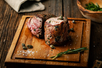 Grilled meat with spices rosemary and capers on a wooden board - 436391556