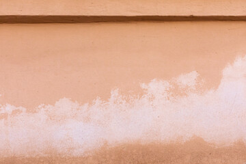 A rough concrete wall of beige color. The background for writing and design. Old weathered light paints