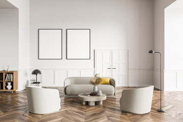 Living room design interior. Modern stylish home area. Two framed mock up posters on white wall. Wooden parquet floor. Armchairs and couch in the middle of the room.