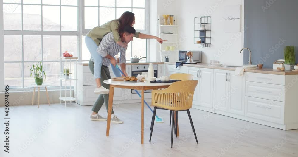 Sticker Young couple having fun while cleaning kitchen