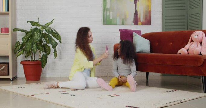 Young African-American woman and her little daughter playing at home