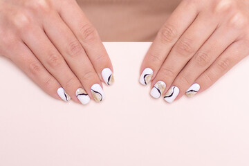 Beautiful female hands with luxury golden manicure nails, white gel polish, with copy space