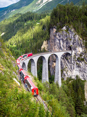 Bernina express train moves on Landwasser Viaduct, Switzerland. Railroad and travel in Swiss Alps...