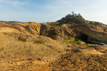 In the photo you can see the sandy hills. Mountainous, desert area. No greenery. Grass scorched by the sun at the top and at the foot of the hill. Clear blue sky. Minimalism.