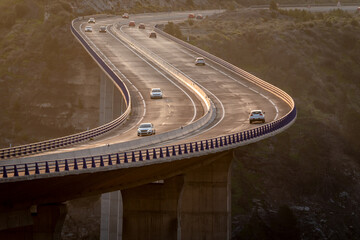 Curvy viaduct and cars going both ways at sunrise.