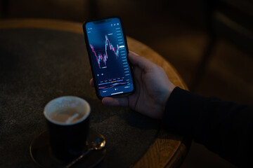 Businessman monitoring real time stock market data on smartphone while sitting outdoors