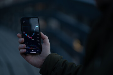 Businessman or trader analyzing forex chart and financial data on mobile phone screen