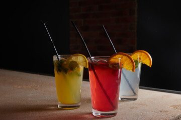 on the table, soft drinks, various cocktails, a glass with a straw and a slice of lemon, a blurred background