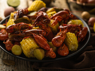 Pictured is a plate with boiled crayfish and corn. Bright colors. Wooden table. Close-up. Macro photography. There are no people in the photo. Color image.