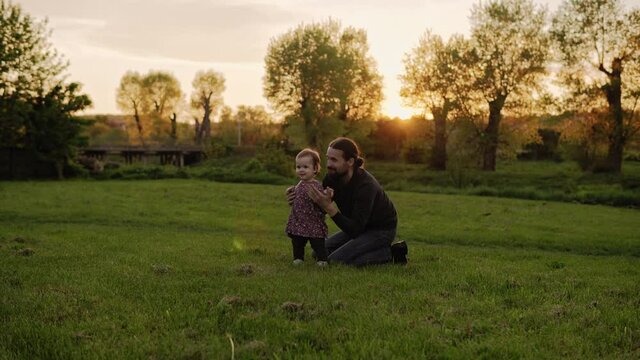 people in the park. happy family silhouette at sunset. dad swinging baby by hte hands have spend time. parents and fun children walking outdoors in open air. Fathers day, childhood, parenthood concept