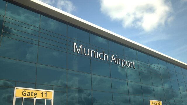 Landing airplane reflects in the modern windows with Munich Airport text