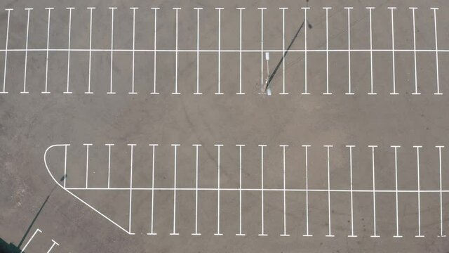 top shot large empty parking lot. dry asphalt sunny day. cinematic camera movement around an empty ground parking lot. white line markings on wet asphalt. 4k footage