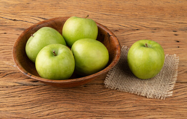 Green apples in a bowl over wooden table