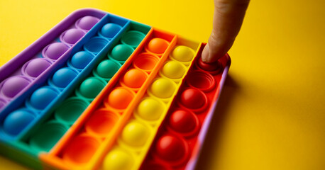 fingers hitting bubbles in a colorful poppit game. Close up photo of poppit, antistress toy