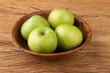 Green apples in a bowl over wooden table